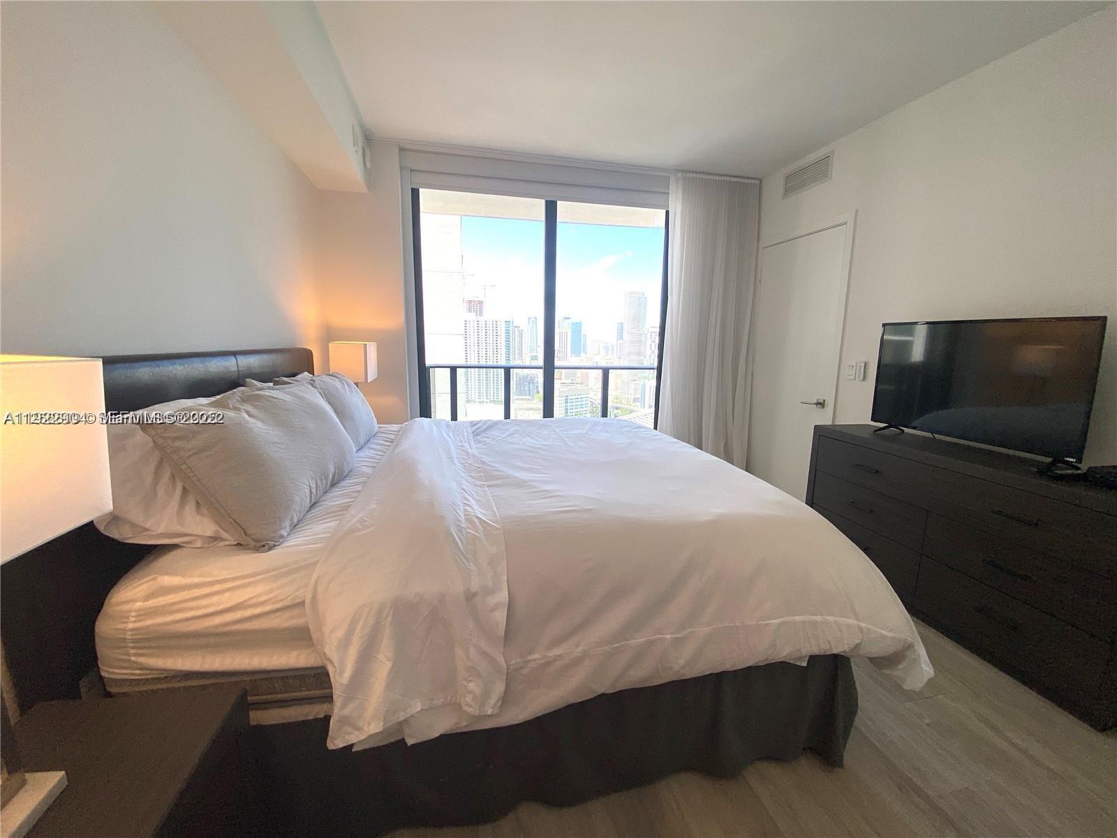 55 Southwest 9th Street, Unit 3001 Miami, FL 33130 - Photo 12 of 28 a bedroom with a bed and flat tv screen on the dresser
