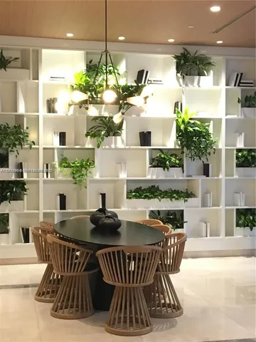 a dining room with furniture a floor to ceiling window and potted plants