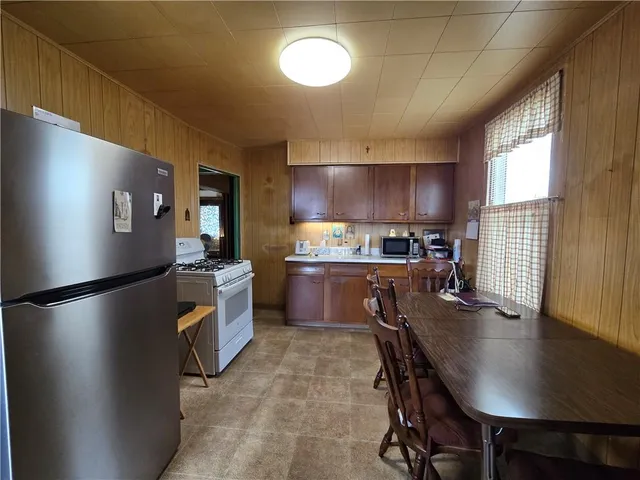 a kitchen with granite countertop a refrigerator a stove a sink dishwasher a dining table and chairs with wooden floor