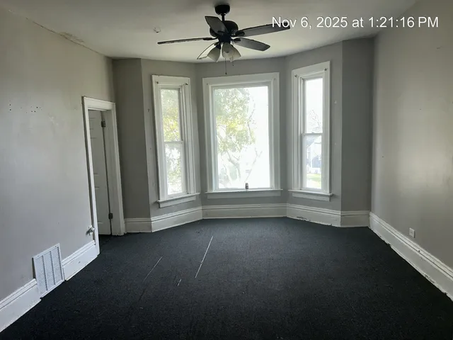 an empty room with a window and a ceiling fan