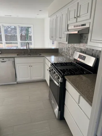 a kitchen with granite countertop a stove sink and cabinets