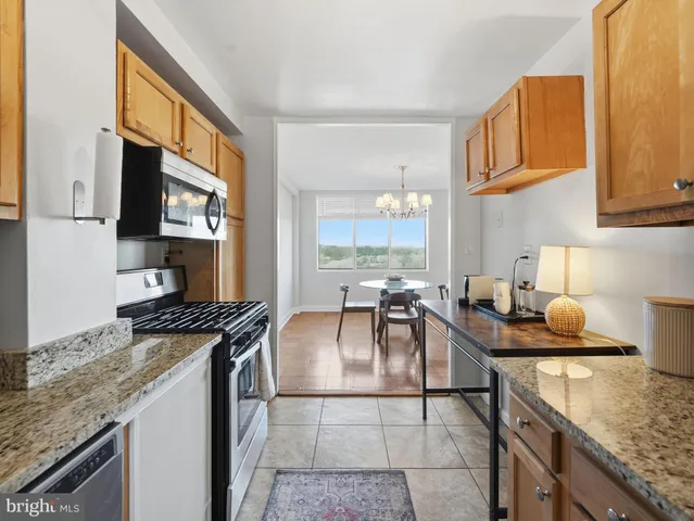 a kitchen with stainless steel appliances granite countertop a stove top oven a sink a dining table and chairs