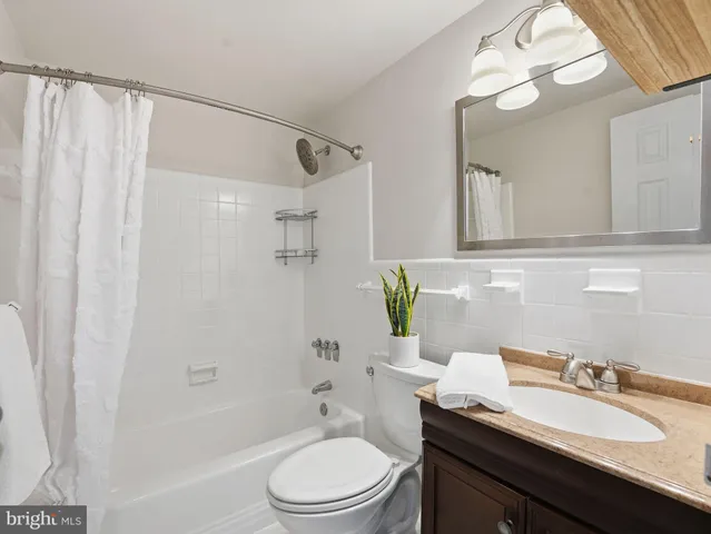 a bathroom with a granite countertop sink toilet a mirror and shower