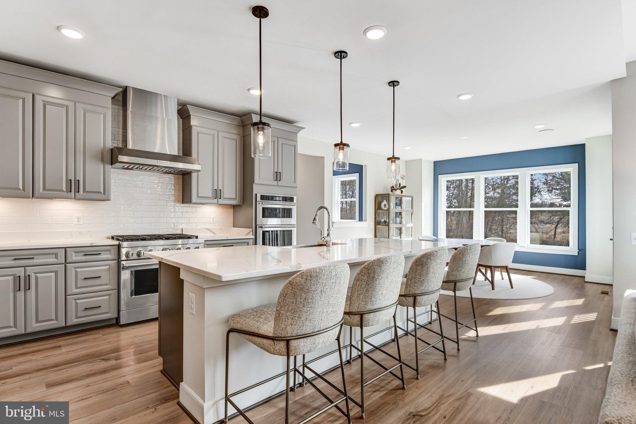 43199 Dogan Rdg Place Centreville, VA 20120 - Photo 24 of 86 a open kitchen with stainless steel appliances granite countertop a stove top oven a refrigerator a sink and white cabinets with wooden floor