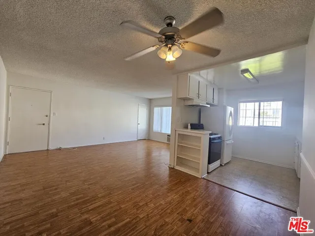 a view of an empty room with a window and wooden floor