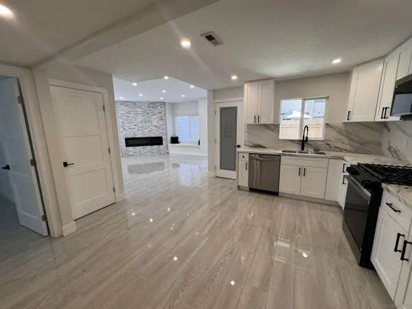 a kitchen with stainless steel appliances granite countertop a stove top oven a sink dishwasher and a refrigerator with wooden floor