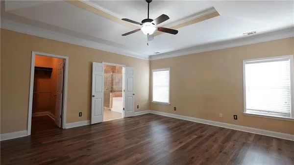 an empty room with wooden floor cabinet and windows