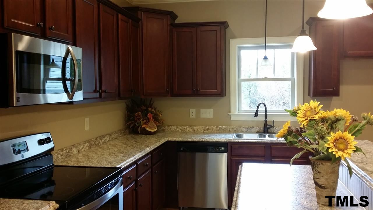 665 Tilghman Road Coats, NC 27521 - Photo 9 of 25 a kitchen with granite countertop a sink a stove and a microwave