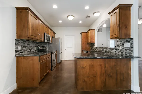 a kitchen with stainless steel appliances granite countertop a stove a sink and a microwave