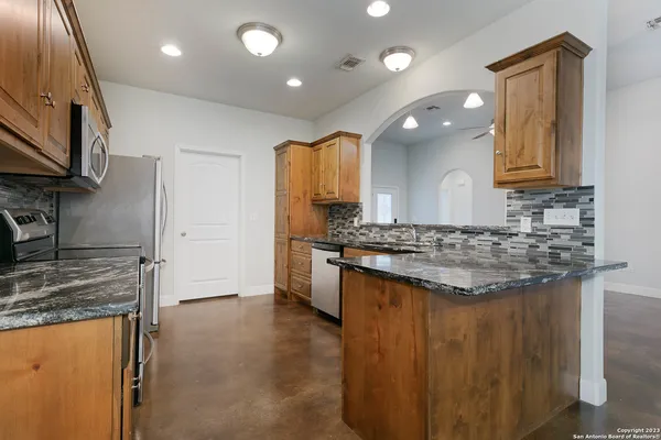 a kitchen with kitchen island granite countertop wooden cabinets and a stove