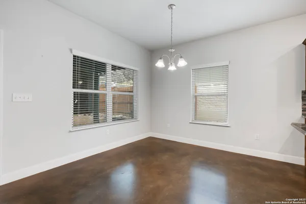 an empty room with wooden floor exposed radiator and windows