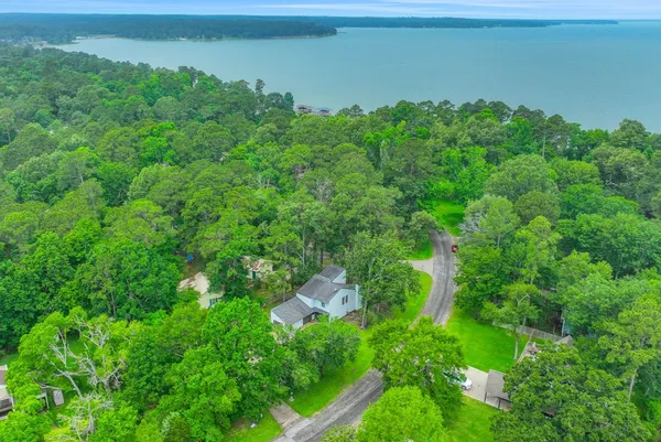 an aerial view of a houses with outdoor space and trees all around