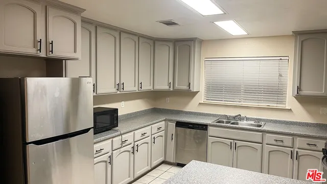 a kitchen with granite countertop a refrigerator sink and cabinets