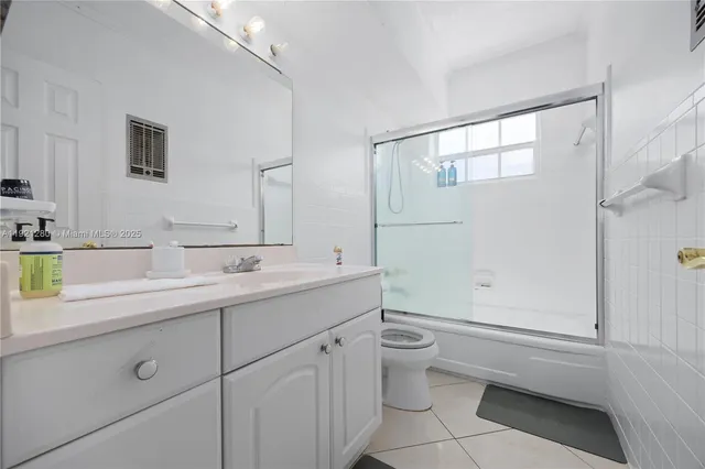 a bathroom with a granite countertop sink a toilet and shower