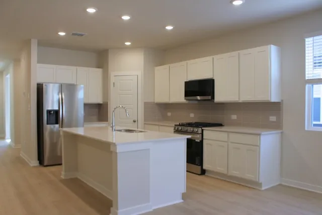 a kitchen with stainless steel appliances granite countertop a stove a sink and a refrigerator