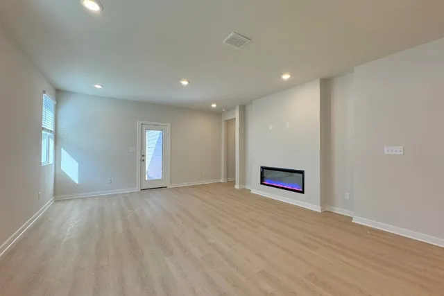 an empty room with wooden floor closet and windows
