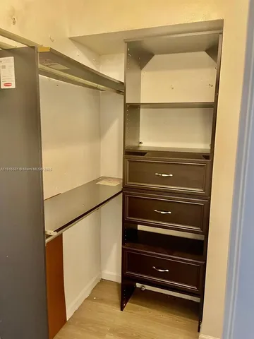 a kitchen with granite countertop a refrigerator a sink and wooden cabinets
