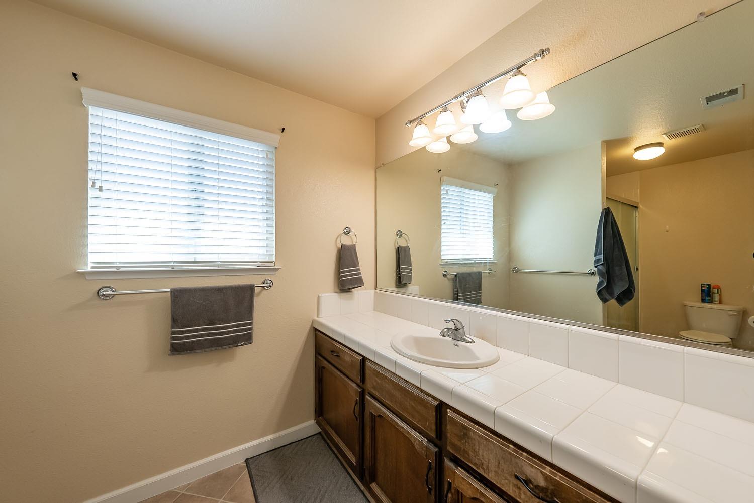 653 Meadow Lane Lemoore, CA 93245 - Photo 22 of 43 a bathroom with a sink a large mirror and a bathtub