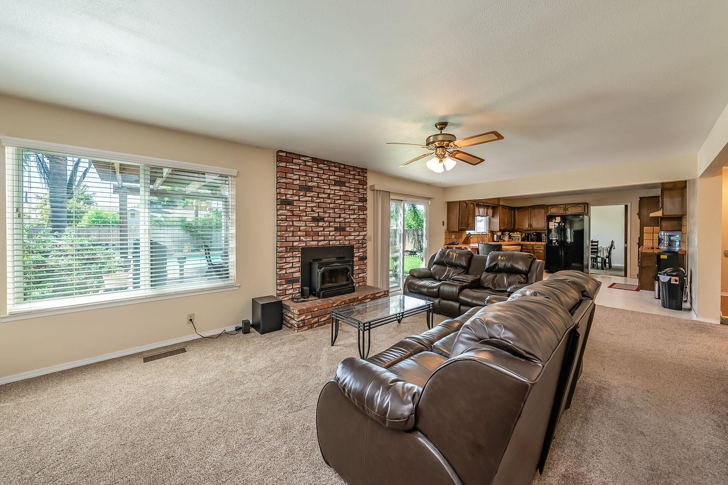 653 Meadow Lane Lemoore, CA 93245 - Photo 9 of 43 a living room with furniture ceiling fan and a fireplace