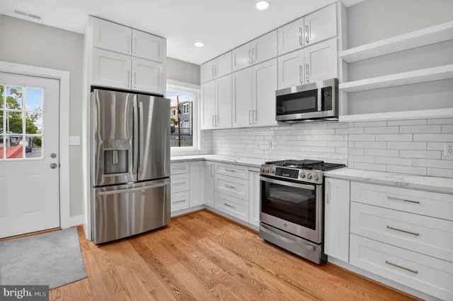 a kitchen with stainless steel appliances and wooden floor