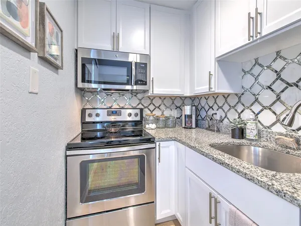 a kitchen with granite countertop a stove top oven microwave and cabinets