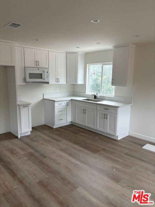 7072 Summitrose Street Tujunga, CA 91042 - Photo 5 of 10 a kitchen with stainless steel appliances granite countertop a stove top oven a sink and white cabinets with wooden floor