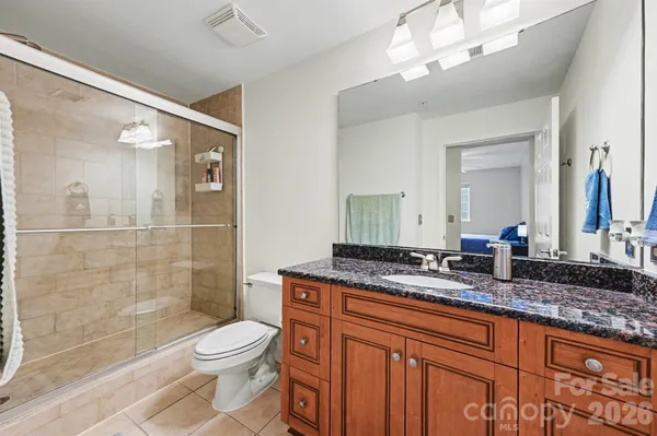 a bathroom with a granite countertop sink a toilet a mirror and shower