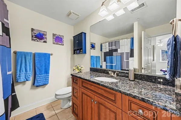a bathroom with a granite countertop sink mirror vanity and toilet