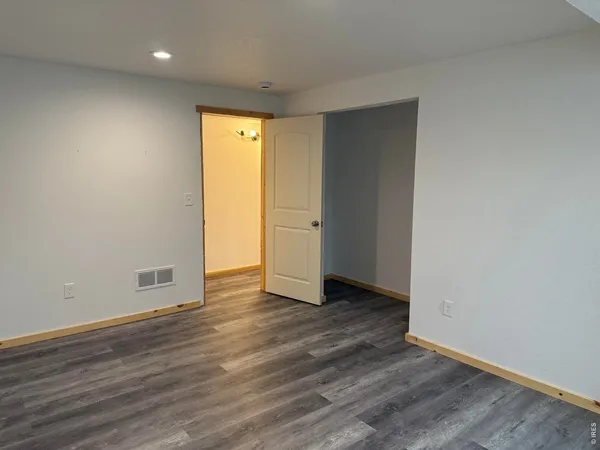 a view of an empty room with wooden floor and closet