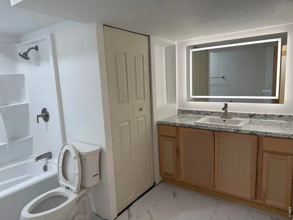 a bathroom with a granite countertop sink toilet and shower