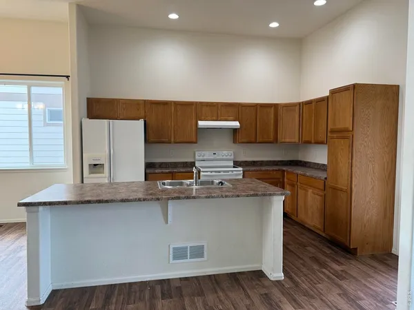 a kitchen with stainless steel appliances granite countertop a sink a stove a refrigerator and cabinets with wooden floor