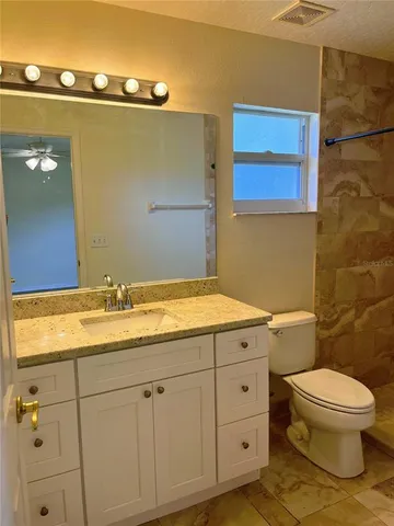 a bathroom with a granite countertop sink toilet and shower