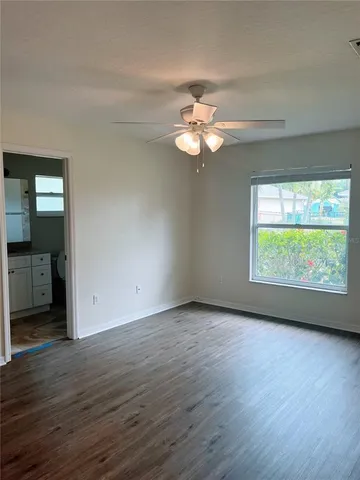 an empty room with wooden floor and a ceiling fan