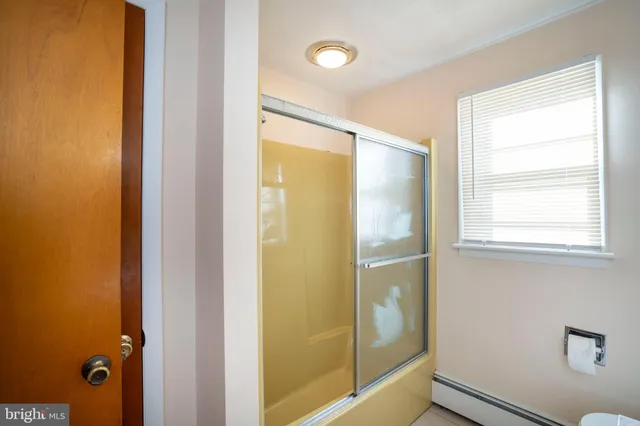 a bathroom with a glass shower door and a window