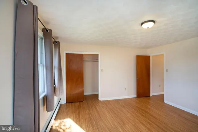 a view of an empty room with wooden floor and a window