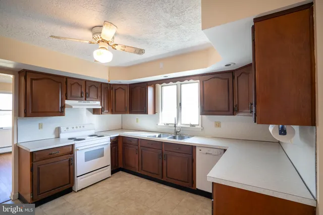 a kitchen with a sink dishwasher a stove a microwave oven and a dining table with wooden floor