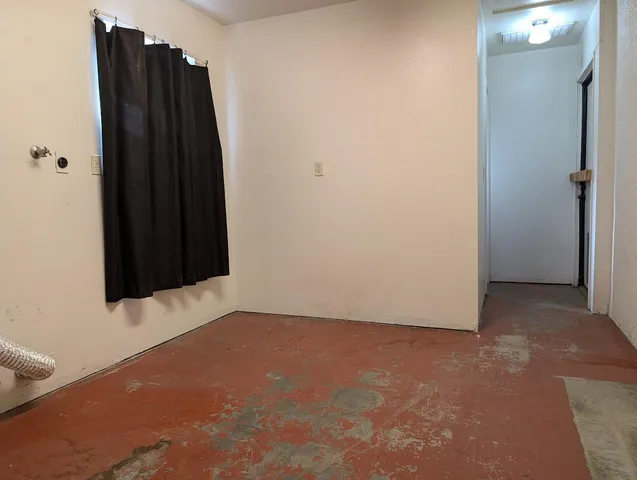 an empty room with a wooden door and a shower