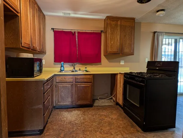 a kitchen with stainless steel appliances granite countertop a stove a sink dishwasher and a microwave oven with cabinets