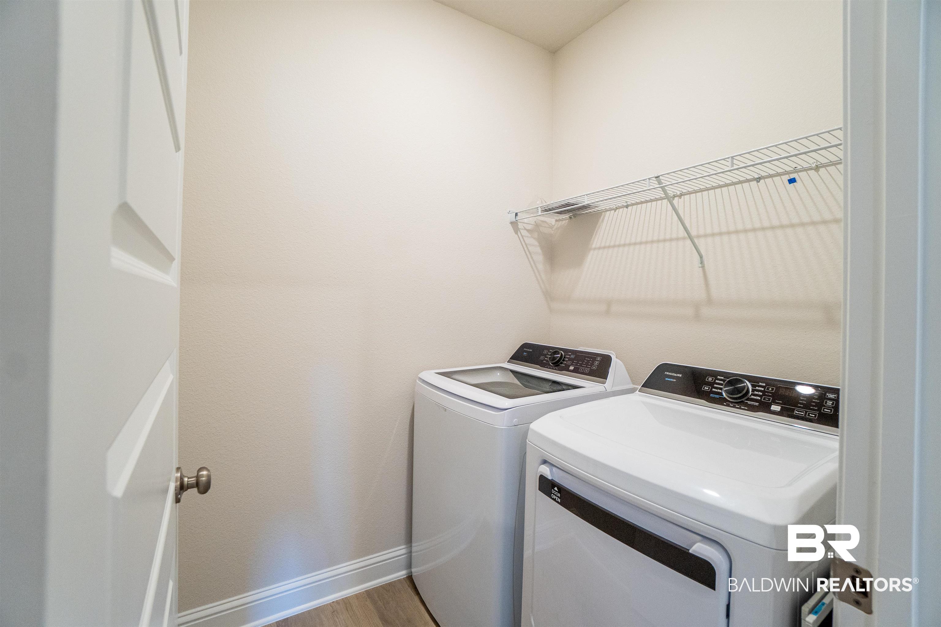 1073 Hayward Loop Foley, AL 36535 - Photo 17 of 18 Dedicated laundry space featuring a white wire shelving unit, wood-finish flooring, and white baseboards