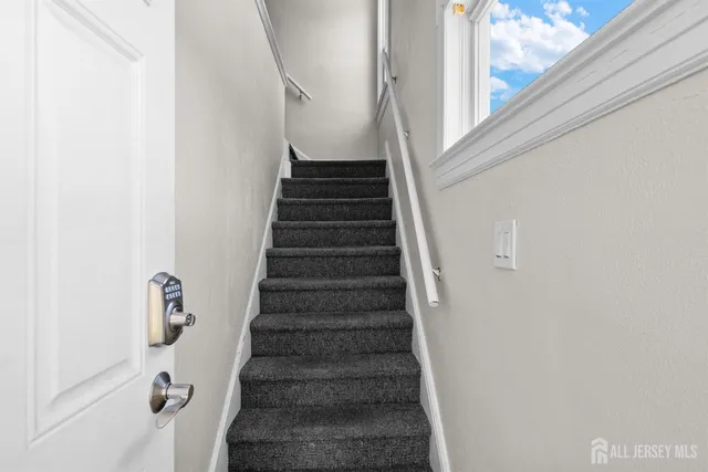 a view of staircase with wooden floor and white walls