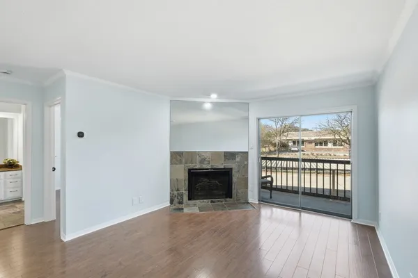 an empty room with wooden floor fireplace and windows
