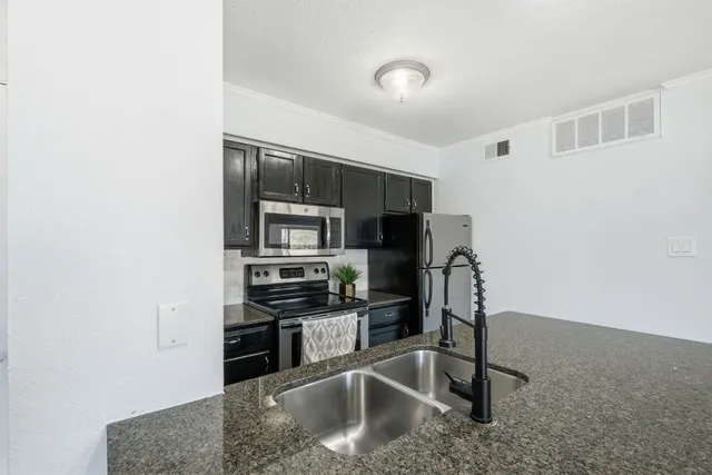 a kitchen with stainless steel appliances granite countertop a refrigerator a sink a stove a microwave and island