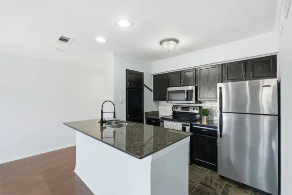 a kitchen with stainless steel appliances granite countertop a refrigerator a sink a stove a microwave and island
