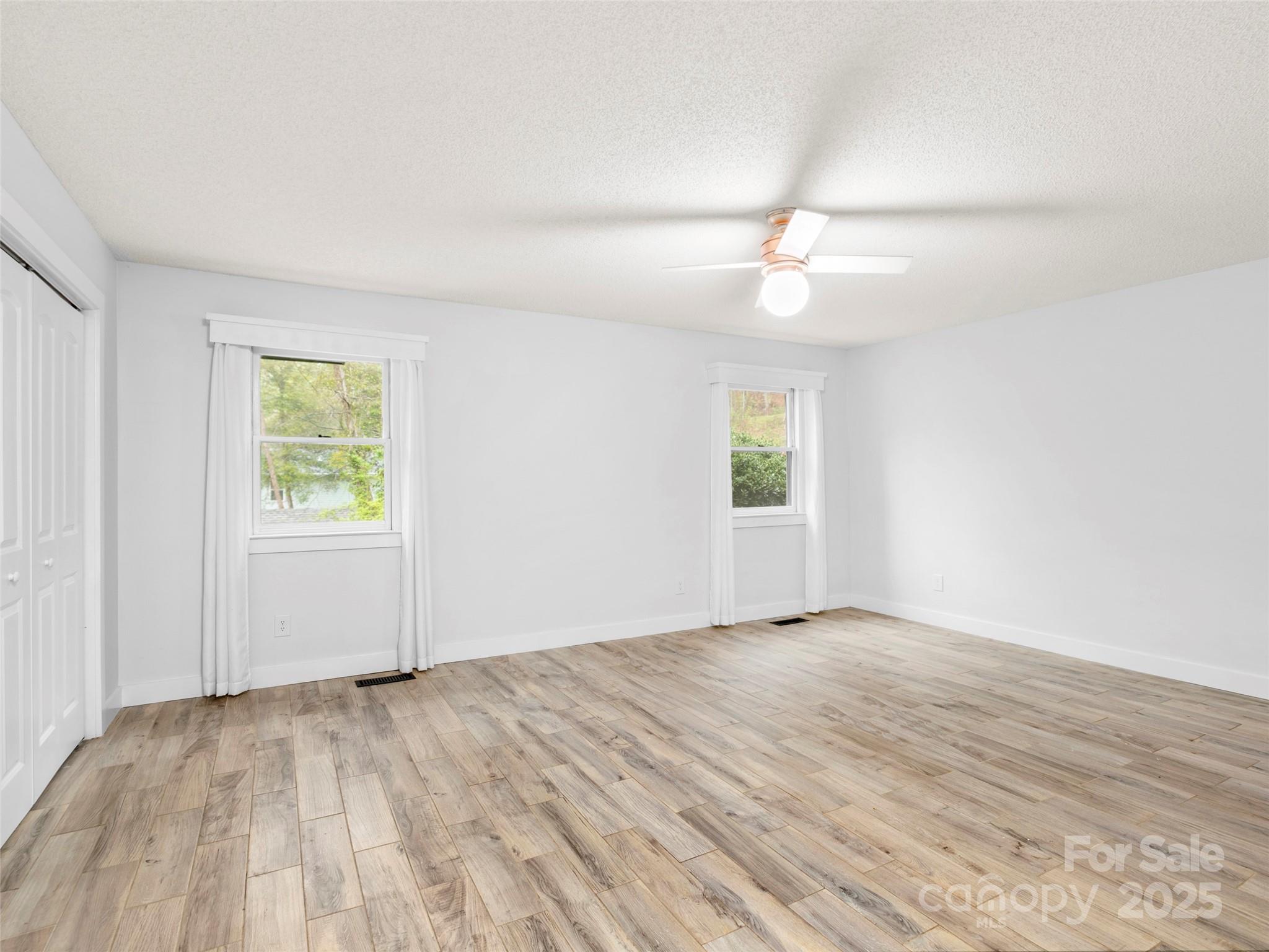 373 Vineyard Road Tryon, NC 28782 - Photo 20 of 46 an empty room with wooden floor ceiling fan and windows
