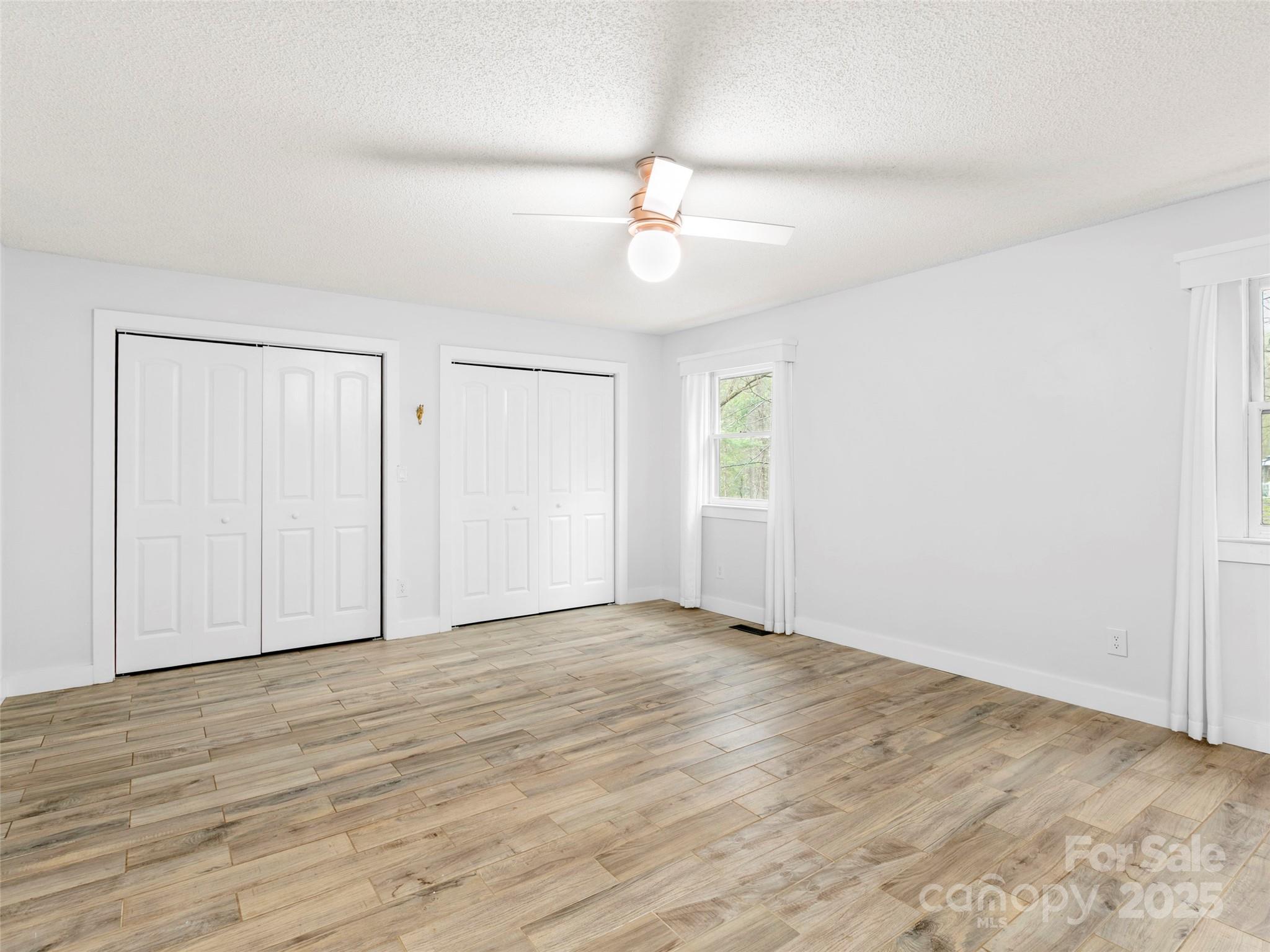 373 Vineyard Road Tryon, NC 28782 - Photo 21 of 46 an empty room with wooden floor ceiling fan and windows