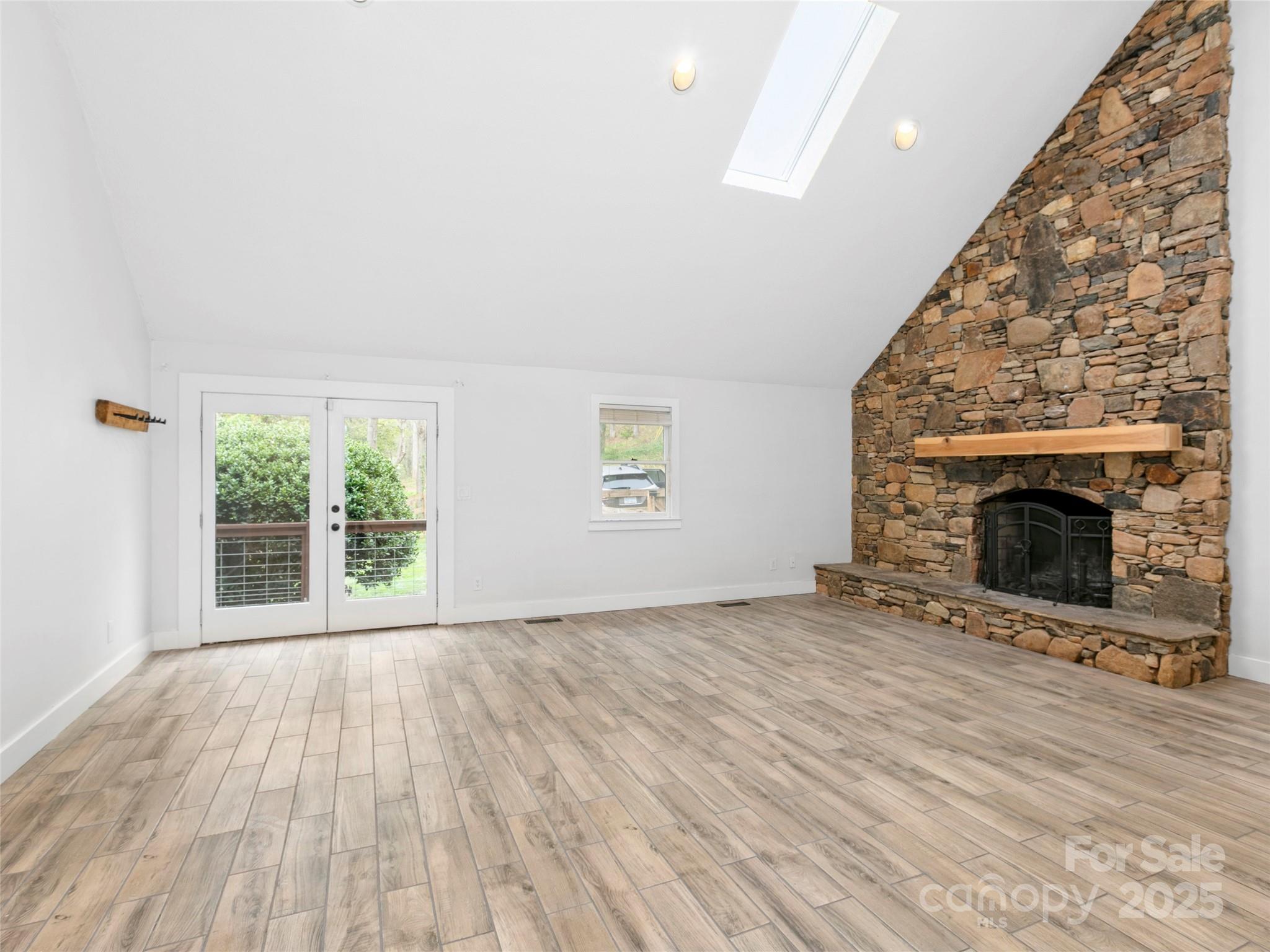 373 Vineyard Road Tryon, NC 28782 - Photo 4 of 46 an empty room with wooden floor fireplace and windows