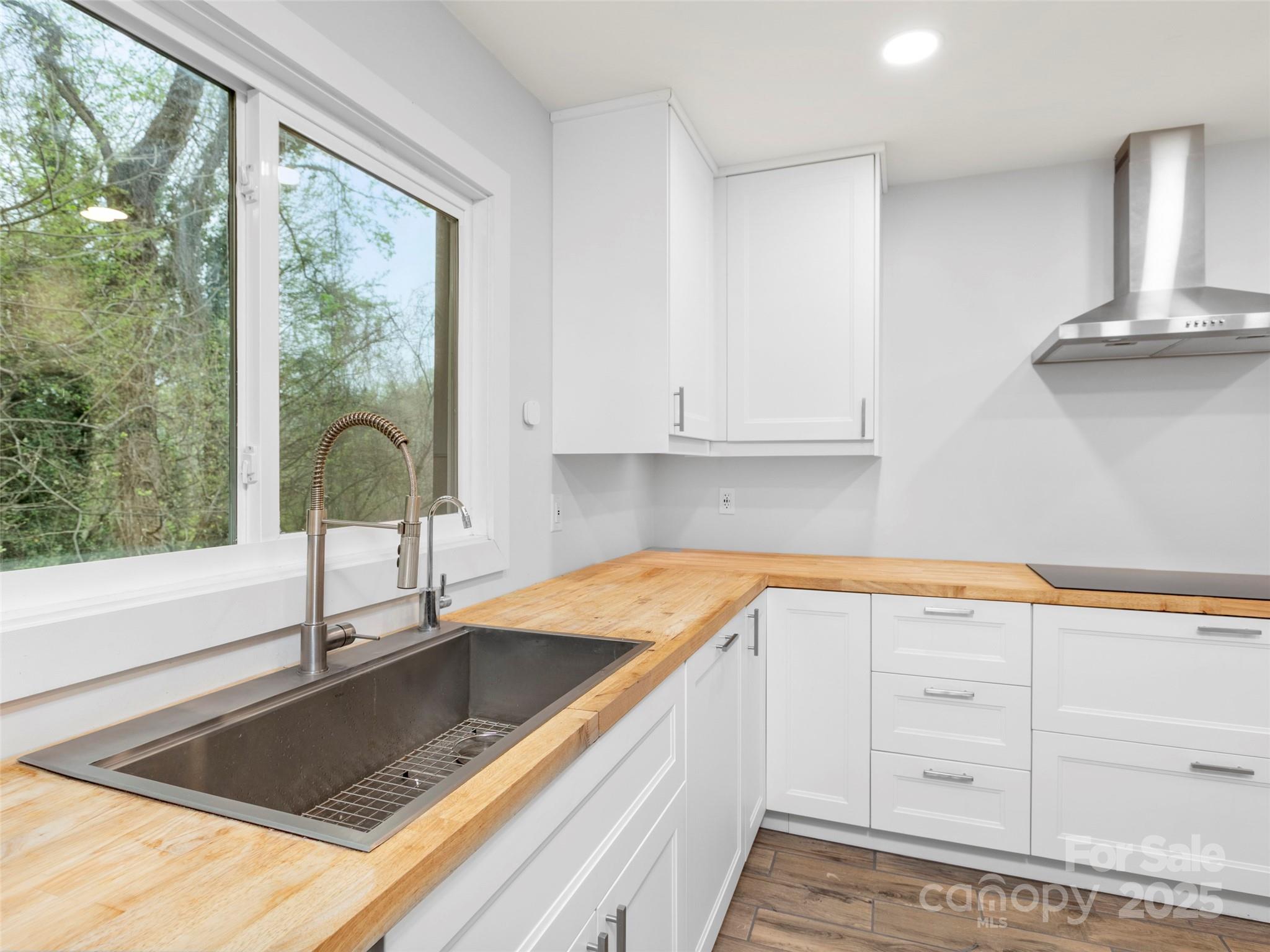 373 Vineyard Road Tryon, NC 28782 - Photo 10 of 46 a kitchen with stainless steel appliances granite countertop a sink a stove and white cabinets with wooden floor