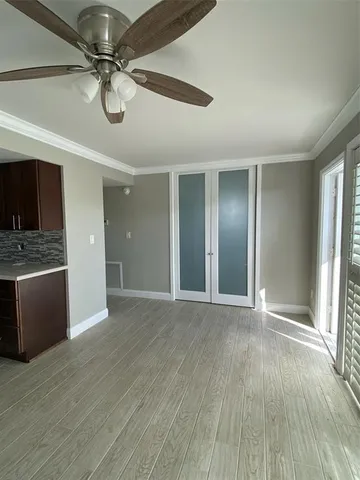 a view of an empty room with glass door and chandelier fan