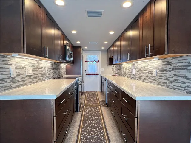 a kitchen with kitchen island granite countertop wooden cabinets a sink and stainless steel appliances