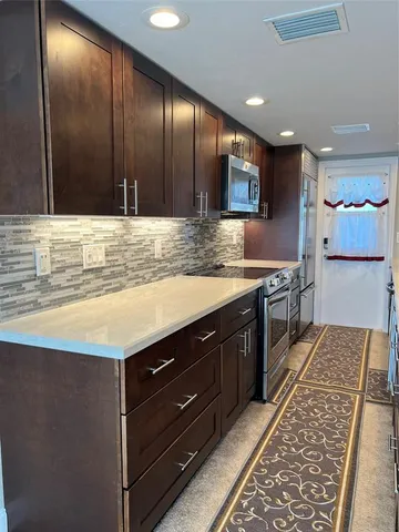 a large kitchen with stainless steel appliances wooden cabinets and a counter top